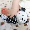 A baby's hand and foot are interacting with a black and white sensory toy. Produktbild-Vorschau