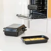 Two black roasting pans are on a white countertop, with an open oven in the background. Voir les images du produit