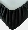A close-up view of the corner of a black fitted sheet with elastic gathering. Produktbild-Vorschau