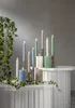 A collection of LED candles in various colors and sizes arranged on a white tiered surface, with ivy vines draped around. Podgląd zdjęcia produktu