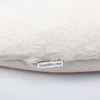 A close-up view of a cream-colored, plush fabric with a small white tag attached. Produktbild-Vorschau