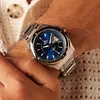 A close-up shot of a man's wrist wearing a silver watch with a blue dial. Produktbild-Vorschau