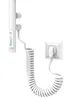 A white electric towel dryer with a coiled power cord plugged into a white wall socket, shown against a white background. Podgląd zdjęcia produktu
