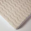 A close-up view of a beige, wavy-patterned mattress topper. Anteprima dell’immagine prodotto