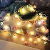 A string of pompom fairy lights draped over a stuffed animal and pillows. Produktbild-Vorschau