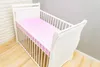 A white baby crib with pink polka dot bedding. Produktbild-Vorschau