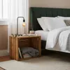 A bedside table setup with a wooden crate as a nightstand, a lamp, books, and a bed with green headboard. Náhled obrázku produktu