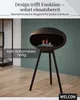 A modern black bioethanol fireplace with a flame is displayed on a tripod stand in a room with a teal wall and wooden floor. Podgląd zdjęcia produktu