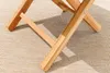 Close-up of the wooden legs of a folding table on a striped rug. Produktbild-Vorschau