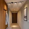 A hallway with a wooden wall panel, a coat rack with clothes, a door, and a framed picture on the wall. Produktbild-Vorschau