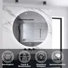 A modern bathroom with a round LED mirror mounted on a marble-patterned wall. Below the mirror are icons representing product features.