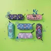 A collection of pencil cases with various cute and whimsical designs, arranged on a bright green background with decorative elements. Produktbild-Vorschau