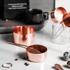 Copper measuring cups and spoons on a marble surface with coffee beans and quail eggs. Produktbild-Vorschau
