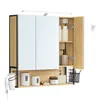 A modern bathroom medicine cabinet with mirrored doors, wooden accents, and integrated lighting, shown with various toiletries and a hairdryer holder. Náhled obrázku produktu
