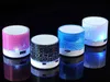 Four colorful, illuminated Bluetooth speakers are arranged in a line against a black background. Produktbild-Vorschau