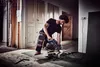A man is using a miter saw in a room with wooden doors and flooring. Anteprima dell’immagine prodotto