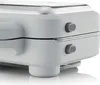 A close-up view of the side of a white and silver waffle maker, showing two gray buttons with ribbed texture. Produktbild-Vorschau