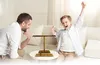 A father and son are playing a ring toss game on a coffee table in a living room. Náhled obrázku produktu