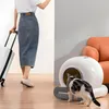 A person is walking with a suitcase, while a cat uses an automatic litter box next to an orange sofa. Anteprima dell’immagine prodotto