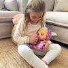 A young girl is sitting on a rug, holding a doll. Produktbild-Vorschau