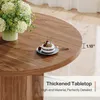 A close-up view of a round wooden table with a small cake and a vase of flowers. Produktbild-Vorschau