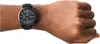 A close-up shot of a black Armani watch on a person's wrist. Voir les images du produit