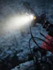 A close-up of a bicycle handlebar with a bright light illuminating the snowy surroundings. Produktbild-Vorschau