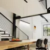 A modern dining room with a long wooden table and black chairs, illuminated by a linear pendant light. Produktbild-Vorschau