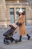 A woman pushing a stroller on a sidewalk in front of a building. Náhled obrázku produktu