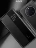 A black leather phone case with a transparent window is shown, displaying the time and date. Produktbild-Vorschau