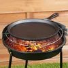 A cast iron skillet is placed on a grill over hot coals, with a wooden fence in the background. Produktbild-Vorschau