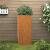 A tall, rectangular planter with a plant inside, placed on grass in front of a wooden fence. Podgląd zdjęcia produktu