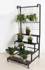 A black metal plant stand with multiple tiers, holding various potted plants. Podgląd zdjęcia produktu