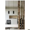 Two black pendant lights hang above a white desk in a modern office space, with birch tree trunks used as a decorative partition. Produktbild-Vorschau