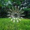 A kinetic wind spinner made of stainless steel is displayed in a grassy garden with trees in the background. Anteprima dell’immagine prodotto