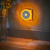 A night light plugged into a wall outlet, casting a warm glow on the wall and floor. A vase with plants is visible on the left. Produktbild-Vorschau