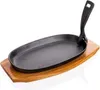 A cast iron oval griddle pan with a black handle, placed on a wooden board. Voir les images du produit
