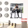Fitnessstudio-Wanddekoration mit einer Collage einer Frau in schwarzer Activewear auf einem Treppensteiger, mit Gewichtsplatten, einer Langhantel und einer Trainingsbank im Vordergrund Anteprima dell’immagine prodotto