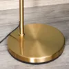 Close-up of the base of a gold floor lamp on a wooden floor. Náhľad obrázku produktu