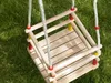 A wooden swing set on green grass. Produktbild-Vorschau
