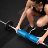 A woman is demonstrating the use of a barbell pad on a weightlifting bar. Náhled obrázku produktu
