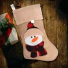 A Christmas stocking with a snowman design is placed on a wooden surface next to a gift-wrapped present. Produktbild-Vorschau