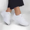A pair of white Skechers sneakers on a person's feet. Voir les images du produit