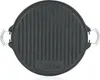 A top-down view of a round, black cast iron grill plate with ridged surface and two spring-like handles on the sides. A logo is visible at the bottom center. Podgląd zdjęcia produktu