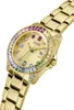 A close-up, studio shot of a gold-colored Guess watch with a rainbow-colored bezel and crystal accents. Produktbild-Vorschau