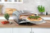 Der Unold Pizzaofen Enzo, ein Tischbackofen aus Edelstahl, zeigt bei geöffneter Tür eine frisch geba Produktbild-Vorschau