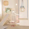 A wooden indoor play structure with a slide, climbing net, and swing, set in a child's room. Anteprima dell’immagine prodotto