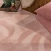 A close-up view of a pink rug with a chevron pattern, next to a woven basket and pillows. Produktbild-Vorschau