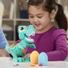 A young girl is playing with a toy dinosaur and Play-Doh eggs. Produktbild-Vorschau