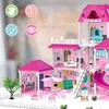 A detailed view of a large, pink, multi-story dollhouse with various accessories, furniture, and small figures, set against a blurred background of bokeh lights. Voir les images du produit